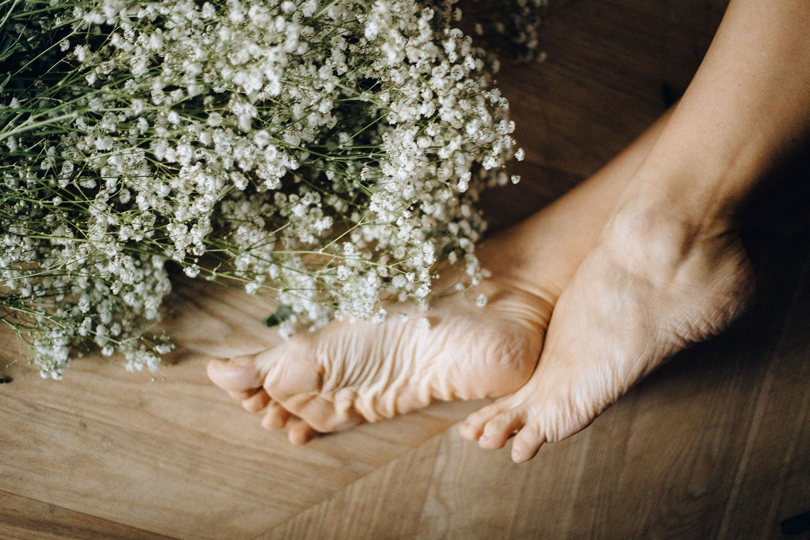 Pied nu sur un parquet avec des fleurs blanches seches